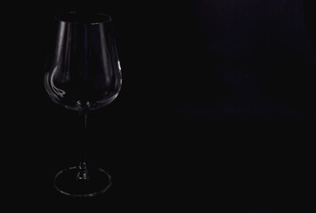 Silhouette of an empty wine glass on a black background, glassware for drinks. Free space.