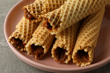 Plate with wafer rolls with condensed milk on gray background