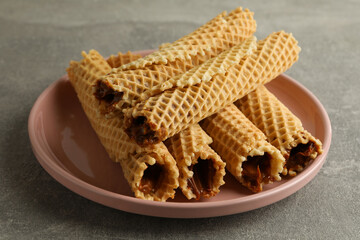 Plate with wafer rolls with condensed milk on gray background