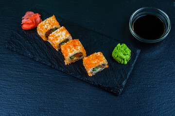 Sushi roll philadelphia with salmon, rice, cheese, cucumber, avocado and caviar on a slate board. Japanese food