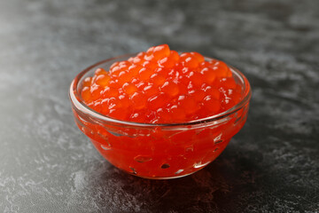 Glass bowl with caviar on black smokey background