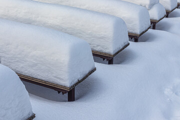 Row of benches covered with snow after a heavy snowfall