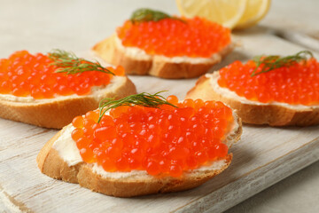 Naklejka na ściany i meble Wooden board with sandwiches with red caviar, close up