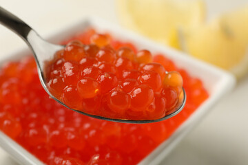 Spoon and bowl with red caviar, close up