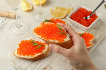 Female hand hold sandwich with red caviar, concept of eating caviar