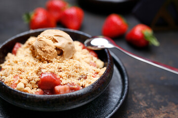 Baked fruit cake served with ice cream. Sweet dessert served in a black bowl. Suggestion to serve the dish.