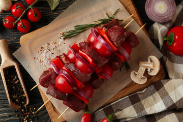 Concept of cooking barbecue with raw shish kebab and ingredients on wooden background