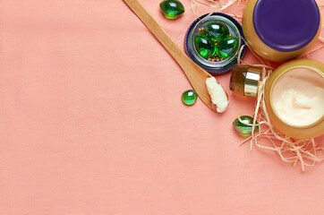 cosmetic cream in a jar and on a wooden spoon with glass green crystals on a scarlet cloth. the view from the top