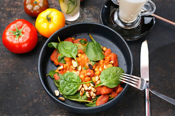 Tomatoes baked with spinach and peanuts.
Food served on a plate, food styling, serving suggestions, culinary photography.