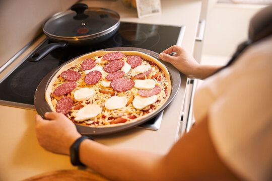 Raw pizza on a baking pan placed on the table