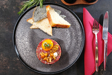 Beef tartare with yolk, pickled mushrooms and mustard. Traditional appetizer.
Serving the dish.