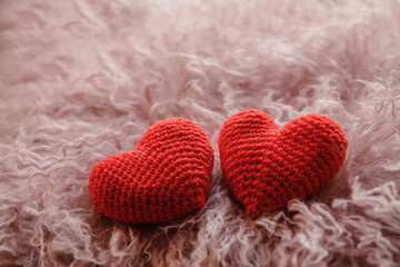 Knitted heart on pink wool.