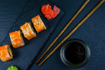 Sushi roll philadelphia with salmon, rice, cheese, cucumber, avocado and caviar on a slate board. Japanese food. Top view