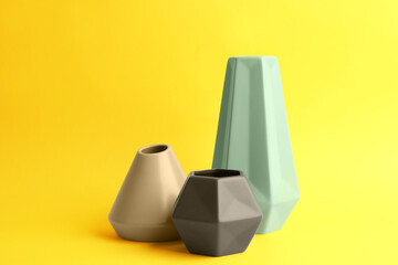 Stylish empty ceramic vases on yellow background
