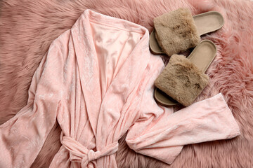 Pair of fluffy slippers and robe on fuzzy carpet, flat lay. Comfortable home outfit