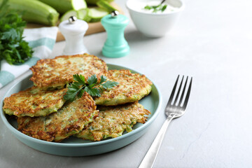 Delicious zucchini fritters served on light table, closeup