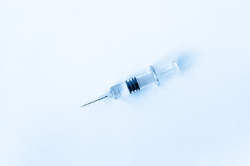 On the table lies a syringe with a needle for medical vaccination on a blue background. Medicine or...