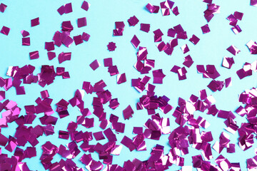 Shiny purple confetti on light blue background, flat lay