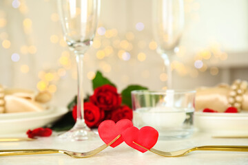 Golden forks with red hearts on white table. Romantic dinner