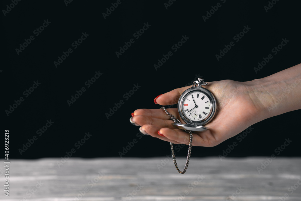 Wall mural old vintage pocket watch on the chain holding by woomen hand. isolated on black background with blan