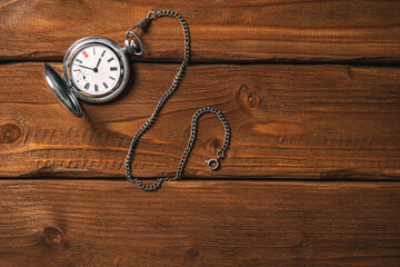Old vintage pocket watch on the chain on wooden table background. Toned. Mock up. Top view. Blank...