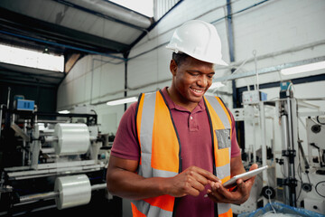 Happy male technician engineer checking process on digital tablet in large factory