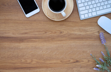 Top view above of Wooden office desk table with keyboard, coffee cup and notebook, phone with equipment office supplies. Business and finance concept. Workplace, Flat lay with blank copy space.