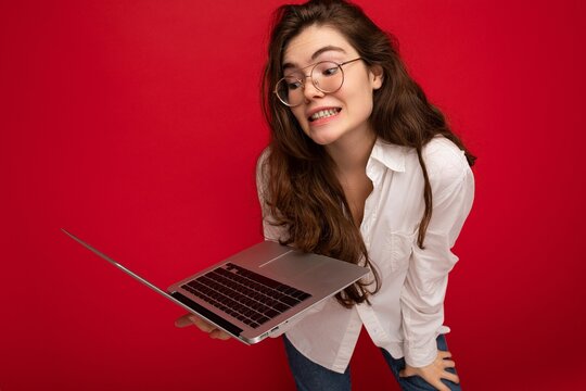 Close-up portrait of overjoyed Beautiful smiling happy young woman holding computer laptop looking at netbook having fun wearing casual smart clothes isolated over wall background