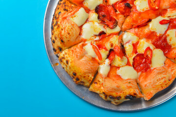 A Pepperoni pizza on a blue background isolated. Traditional Italian cuisine concept, pizza Margarita or Margherita