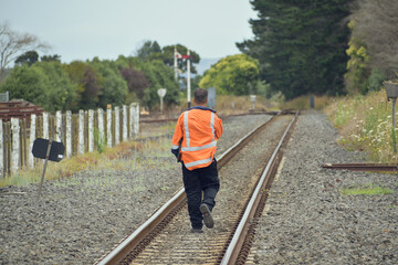 View of railroad worker walking away between rail tracks