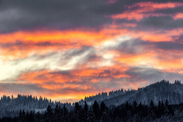 Colorful clouds on evening sky and winter mountains at background