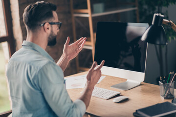 Photo portrait back view of man at online meeting talking to screen with blank space at table in...