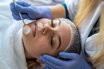 cosmetologist's hand  applying moisturizing cream on face young woman for treatment therapy