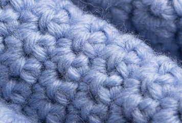 close-up of knitting of front and back loops on a lilac textured woolen background. Handicraft concept.