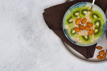 Healthy food for breakfast top view flat lay. Oatmeal porridge with milk, kiwi and almond nuts