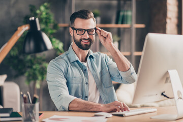 Photo portrait of cool guy touching glasses working on pc at table in modern industrial office...