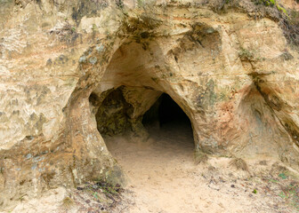 sandstone rock wall and entrance to the cave, the cave is located on the bank of a small river