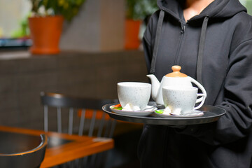 White tea set served by waiter in restaurant or diner. Tea time, black or green tea in small cups. Eating out concept.