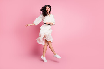 Full length body size photo of cheerful happy girl jumping up in dotted dress smiling dancing isolated pastel pink color background