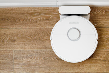 White robotic vacuum cleaner on wooden floor