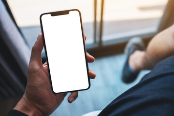 Mockup image of a man holding mobile phone with blank white screen in cafe