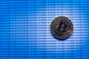Selective focus of gold bitcoin on a paper of binary code.