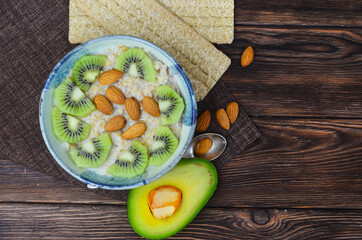 Healthy, natural and hearty breakfast, milk oatmeal porridge with kiwi, avocado  and almonds