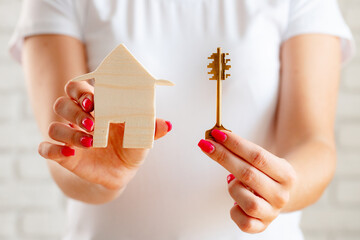 Female hands holding toy wooden house miniature