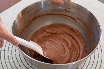 シリコンヘラでチョコレートケーキの生地を混ぜる様子