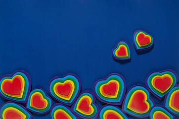 Decorative border of rainbow hearts  on dark blue background, top view.