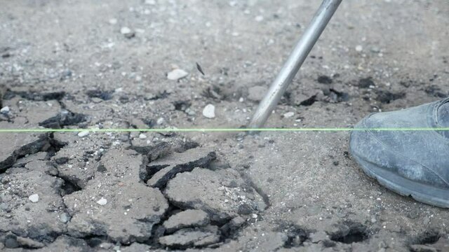 Stick of a demolition hammer penetrating into asphalt and breaking it in slo-mo 
