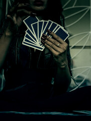  backside ofTarot cards in hand with red nails