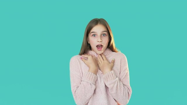 Shocked teenager. Unexpected situation. Why me. Disbelief expression. Puzzled pretty girl holding face hands opening mouth isolated turquoise.