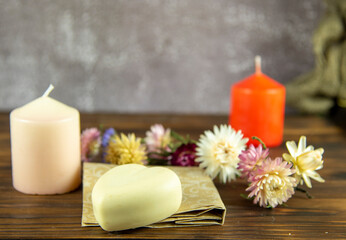 Fototapeta na wymiar Natural handmade skincare. Handmade natural soap, candles and flowers on the dark wooden countertop.